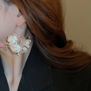 Macro shot of a large silver layered flower metal earring worn on a female ear