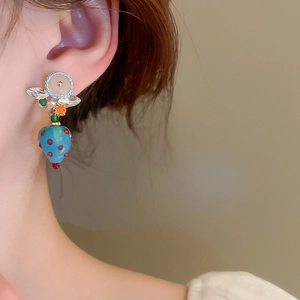 Detail of model wearing a vintage-style blue strawberry resin earring with red dots