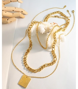 Detailansicht der mehrlagigen Goldketten mit einem abstrakten weiblichen Figurenanhänger