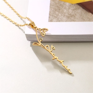 Vertical gold stainless steel necklace detail featuring flower and cursive name pendant