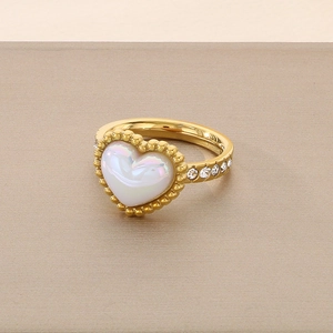 Close-up of heart-shaped white shell ring with gold plating and cubic zirconia accents