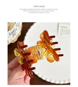 Detail of amber gradient butterfly claw clip with translucent resin and metal spring