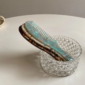 Close-up of marble blue and tortoiseshell acetate hair combs in a glass bowl