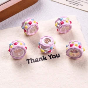Detail shot of five pink resin cake-shaped beads for DIY jewelry making on a fabric bag