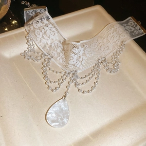 Gros plan d'un choker en dentelle blanche élégante avec glands en perles et pendentif