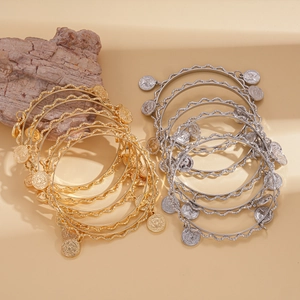 Five-piece metal bangle set featuring wavy edges and vintage coin charms in gold and silver