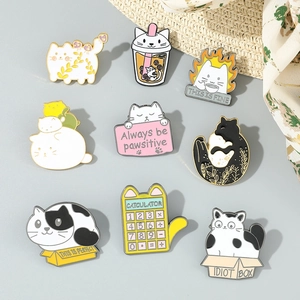 Lot de neuf pin's de chat colorés en émail sur un fond gris neutre