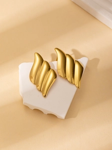 Detailed view of wave-shaped 18K gold-plated steel earrings on white stone display