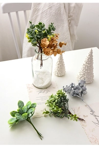 Close-up of assorted artificial eucalyptus stems and pine needles in a glass vase