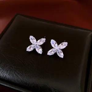 Exquisite silver floral stud earrings with marquise-cut zircons on a black leather texture