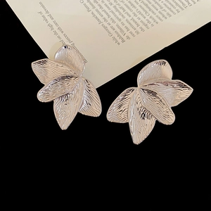 Macro detail of silver layered petal earrings with irregular textured metallic surface