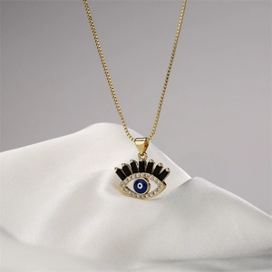 Collana con ciondolo occhio del male dorato e zirconi su elegante sfondo in seta bianca