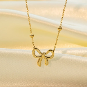 Collier élégant avec pendentif nœud doré et chaîne à billes sur soie jaune douce