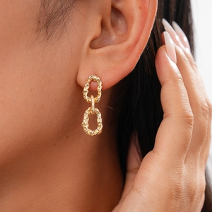 Gros plan de boucles d'oreilles dorées en maille avec finition métallique sur un mannequin