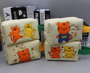 Detail von Cord-Kosmetiktaschen mit Tiger-Stickerei und farbenfrohen Webgriffen