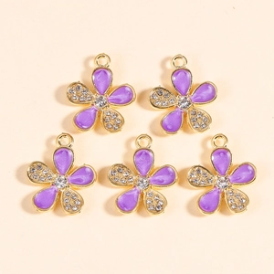 Macro shot of five gold-plated purple enamel flower pendants with white crystals