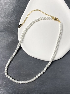 Detail of white pearl necklace with gold-plated K18 lobster clasp on ceramic tray