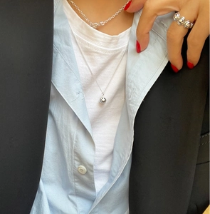 Detail of minimalist 925 sterling silver smiley face necklace and ring on a model