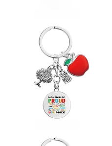 Detail of keychain with apple, owl and tree charms and round engraved gratitude plate