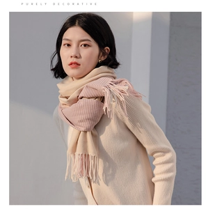 Detailed view of pink and beige plaid tassel scarf worn by model in natural light