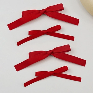 Set of four red satin ribbon hair bows in various sizes on a clean minimalist background