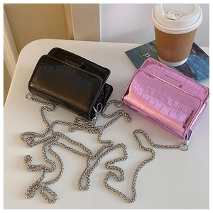 Flat lay of mini crocodile pattern patent leather crossbody bags in black and pink