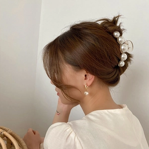 Elegant gold hair claw clip with pearls and matching earrings worn on hair
