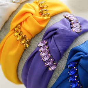 Close-up of knotted fabric headbands in various colors featuring sparkling crystal accents