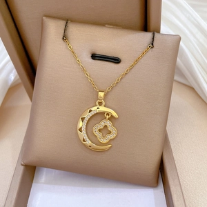 Detailed view of gold moon and clover necklace with inlaid crystals in a jewelry box