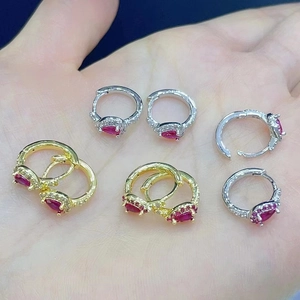 Detailed close-up of pear-shaped red gemstone earrings with sparkling white side stones