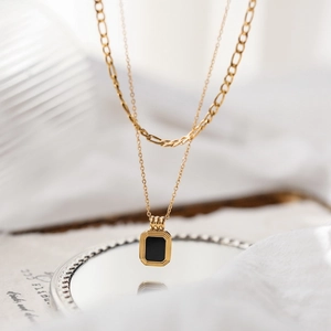 Macro view of double-layer titanium necklace with rectangular black pendant and gold frame