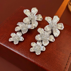 Close-up of vintage silver flower tassel earrings on red-brown leather background