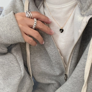 Detail of 925 sterling silver knot ring and heart pendant necklace worn on a hand