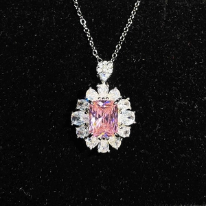 Close-up of pink emerald-cut gemstone pendant with shimmering silver chain on velvet