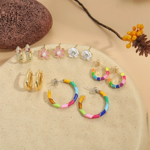 Collection of luxury gold and silver snake-inspired earrings on a stone display