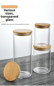 Three sizes of glass storage jars with airtight wooden lids on dark wood surface