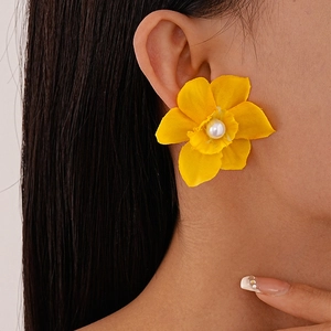 Detail of yellow woven flower earring with pearl center shown on model for sizing