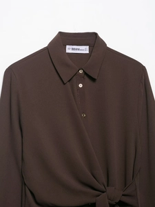 Detail of dark brown crepe shirt featuring textured fabric and decorative front knot