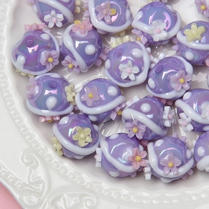 Close-up of purple acrylic cat paw beads with floral patterns for DIY jewelry making