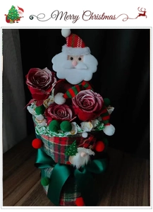 Detail of Christmas flower arrangement with Santa doll, red roses and plaid base