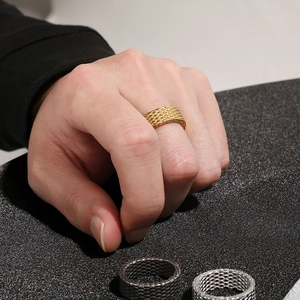 Detailed view of punk style rhombus rings in gold, silver and black woven metal textures