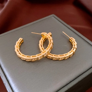 Macro shot of gold snake-style hoop earrings with cubic zirconia on a silk background