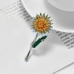 Exquisite dandelion brooch with gold petals and green enamel leaves on a white background
