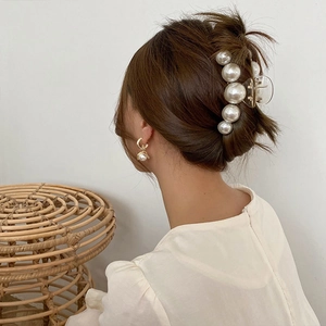 Close-up of elegant pearl hair claw clip and matching earrings worn by a model