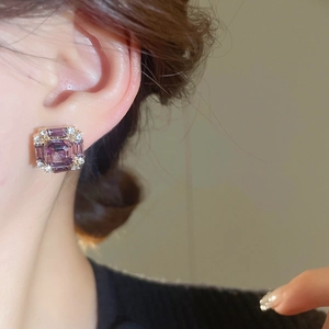 Close-up view of vintage square purple zircon stud earrings worn by a model