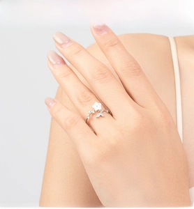 Detailed close-up of a silver camellia ring with white shell petals and zircon leaves