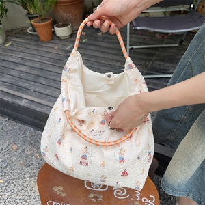 Close-up of cream textured tote bag with rabbit print and striped handles