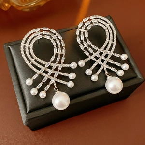 Gros plan de boucles d'oreilles en zircon et perle goutte sur boîte à bijoux