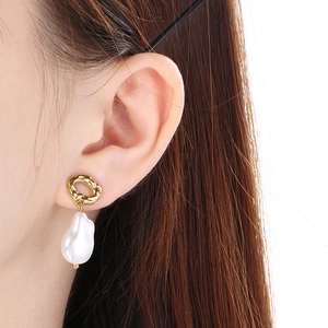 Close-up of elegant gold irregular earrings with white baroque pearls on a model