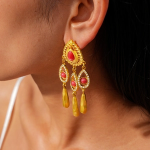 Gros plan sur des boucles d'oreilles vintage en or avec résine rouge et pompons gouttes